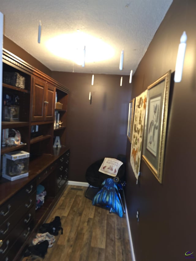 interior space featuring dark wood-style floors, a textured ceiling, and baseboards