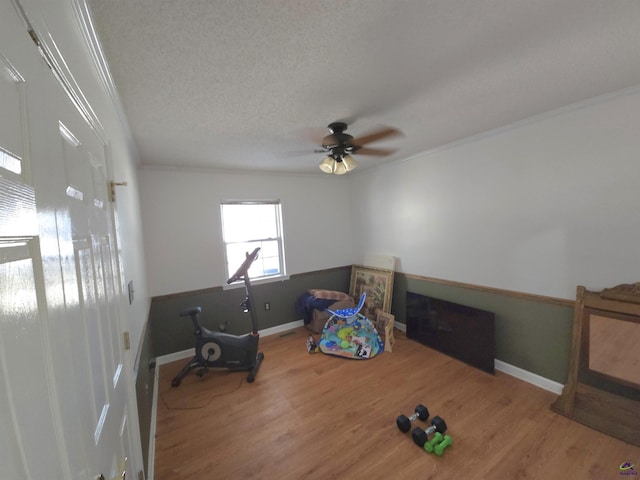 playroom featuring ceiling fan, wood-type flooring, a textured ceiling, and ornamental molding