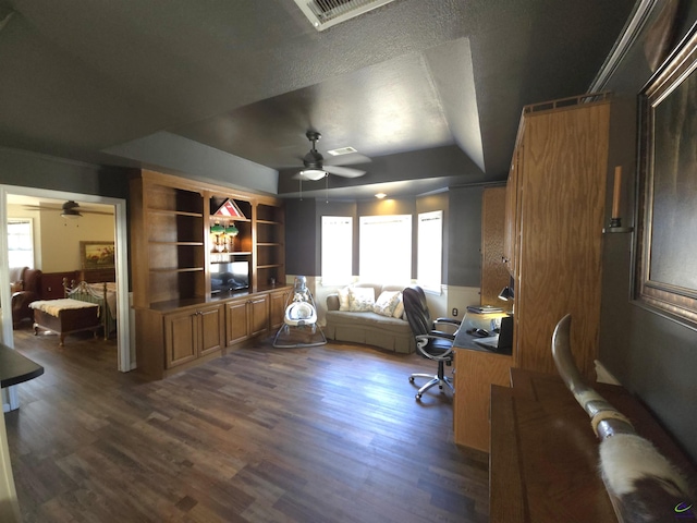 office area with a raised ceiling, dark wood finished floors, and a ceiling fan