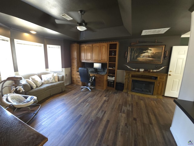 office with ceiling fan, a tray ceiling, dark hardwood / wood-style flooring, and built in desk