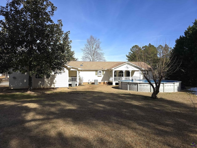 rear view of house featuring an outdoor pool and a lawn