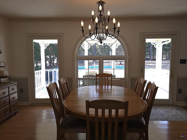 dining room with dark wood-type flooring, an inviting chandelier, and a textured ceiling