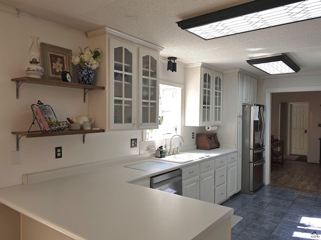 kitchen featuring glass insert cabinets, stainless steel appliances, light countertops, open shelves, and a sink