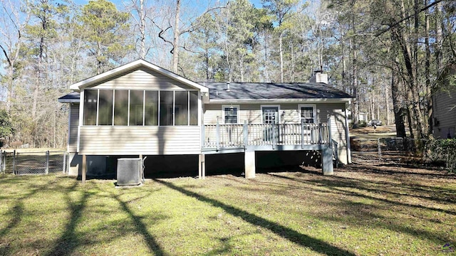 rear view of property featuring central AC unit, a yard, a sunroom, and a deck