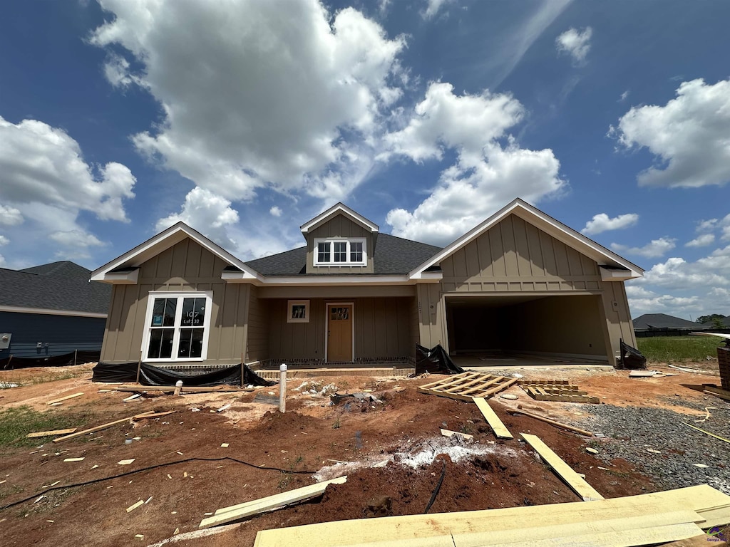 unfinished property featuring driveway, roof with shingles, board and batten siding, and a garage