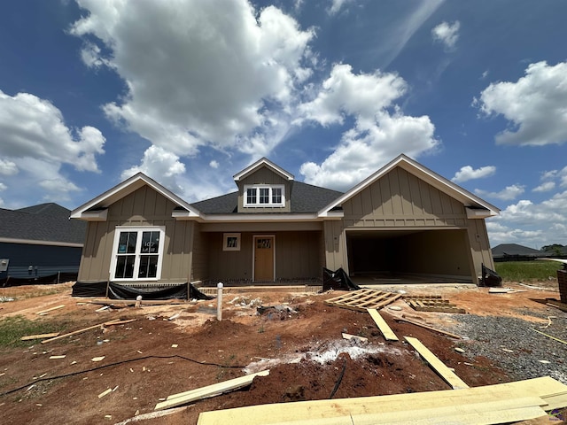 unfinished property featuring driveway, roof with shingles, board and batten siding, and a garage