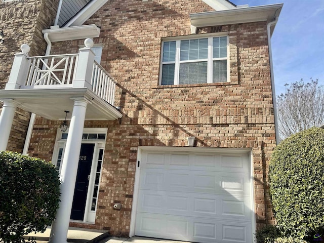 view of exterior entry with a garage and a balcony