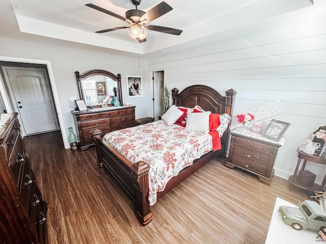 bedroom featuring hardwood / wood-style flooring, ceiling fan, and a raised ceiling