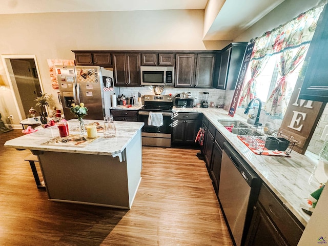 kitchen featuring a kitchen island, appliances with stainless steel finishes, a breakfast bar area, and light hardwood / wood-style floors