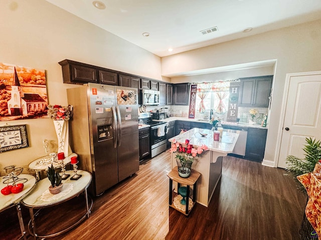 kitchen with sink, hardwood / wood-style flooring, a breakfast bar area, appliances with stainless steel finishes, and a kitchen island