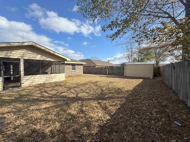 view of yard featuring a sunroom and a storage unit