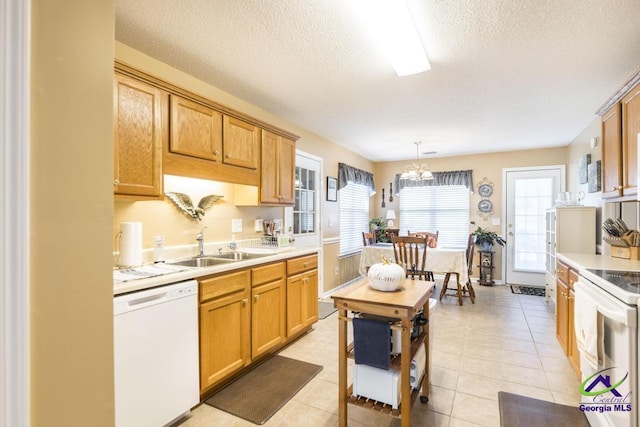 kitchen featuring sink, a textured ceiling, hanging light fixtures, light tile patterned floors, and white appliances