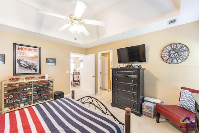 carpeted bedroom featuring ceiling fan and a tray ceiling