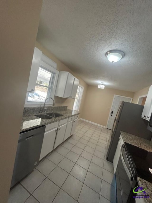 kitchen with white cabinetry, dishwasher, sink, and light tile patterned floors