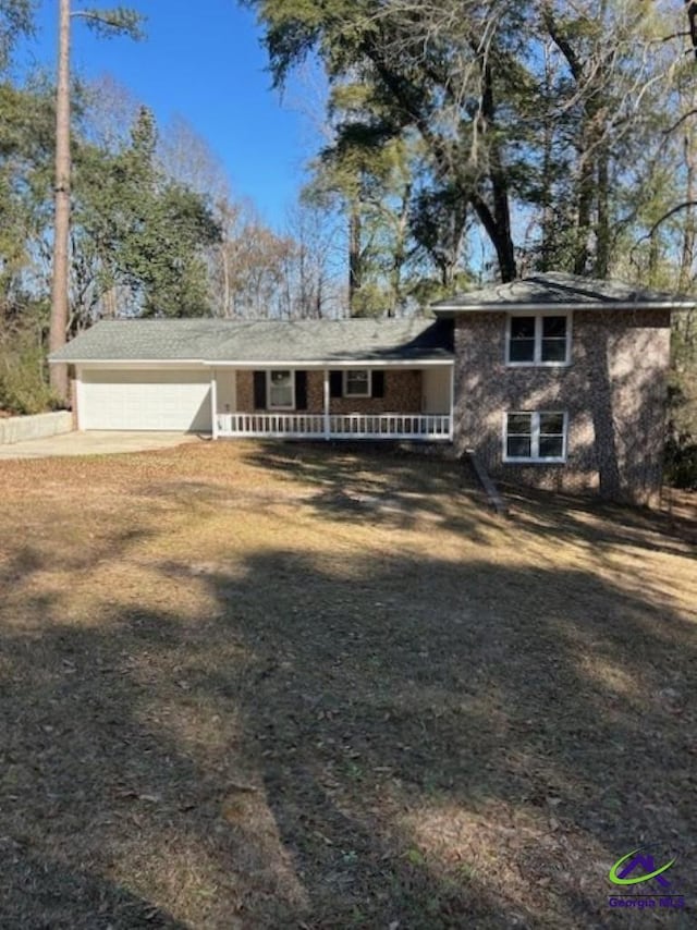 view of front of property featuring a garage, a front lawn, and a porch