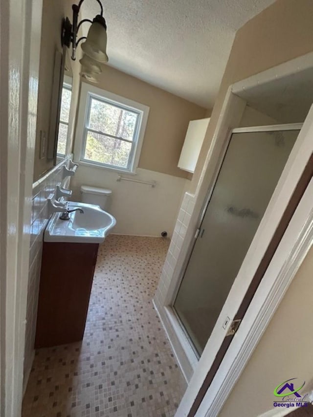 bathroom with walk in shower, vanity, toilet, and a textured ceiling