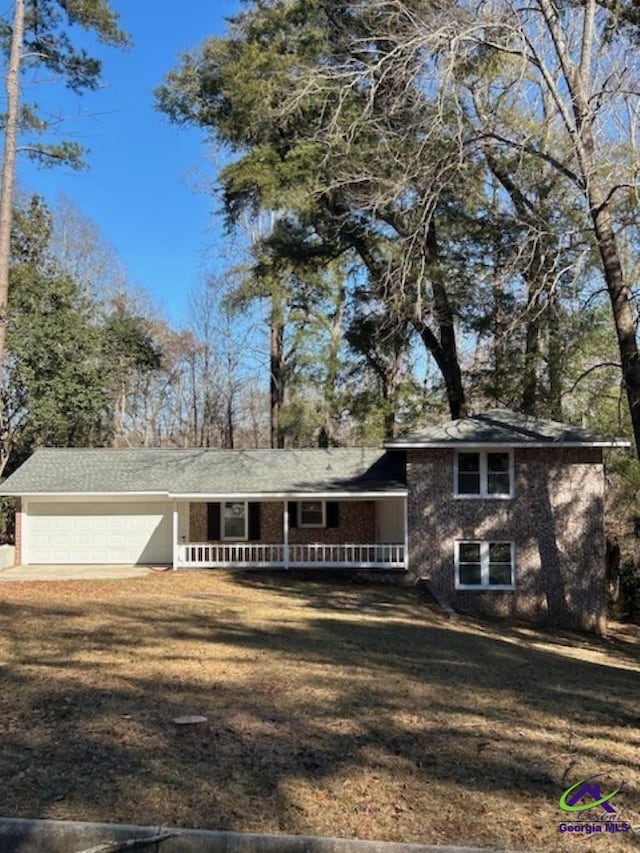 view of front of home with a garage, a front yard, and a porch