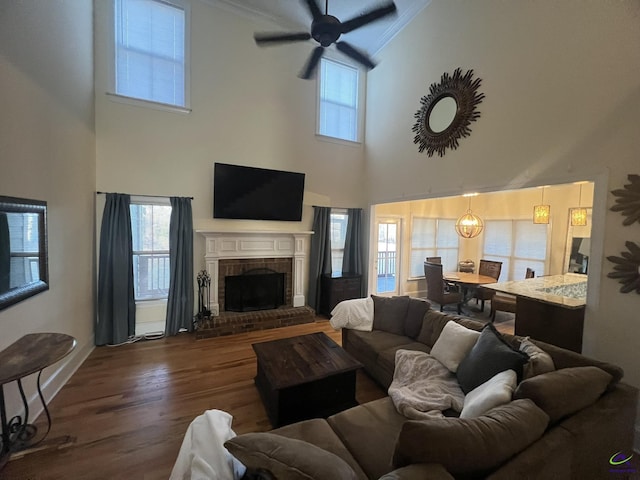 living room with a wealth of natural light, a fireplace, a ceiling fan, and wood finished floors