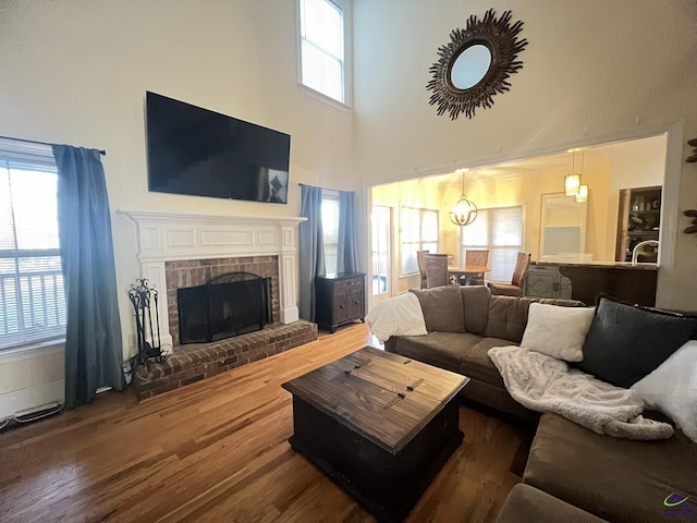 living room featuring dark wood-type flooring, a brick fireplace, and a towering ceiling