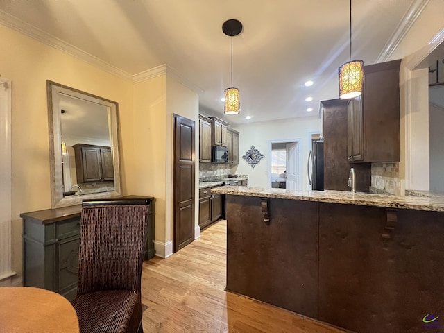 kitchen with black microwave, crown molding, dark brown cabinetry, and pendant lighting