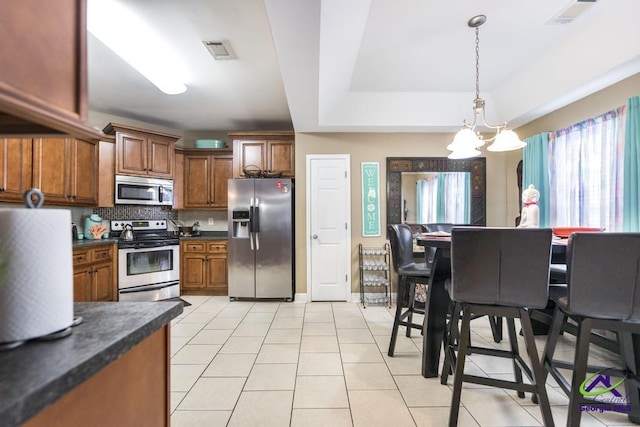 306 Lovorn Cir, Warner Robins, GA 31088 - kitchen with stainless steel appliances, dark countertops, a chandelier, light tile patterned floors, and backsplash