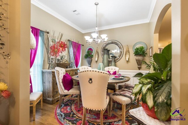 306 Lovorn Cir, Warner Robins, GA 31088 - dining area with ornamental molding, a chandelier, arched walkways, and wood finished floors