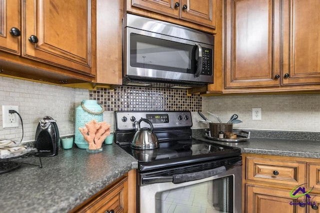 306 Lovorn Cir, Warner Robins, GA 31088 - kitchen with stainless steel appliances, brown cabinets, dark countertops, and tasteful backsplash