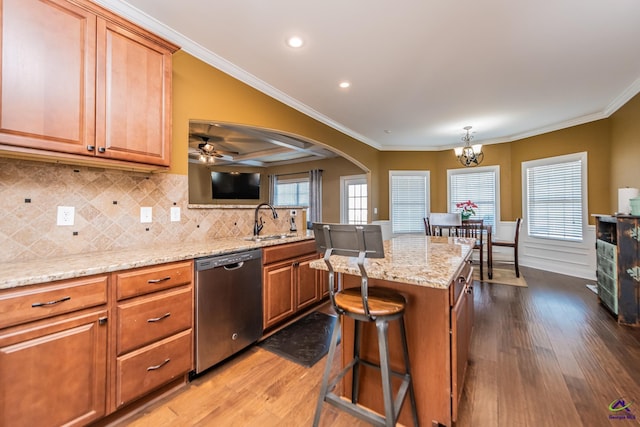 kitchen with sink, crown molding, a breakfast bar, dishwasher, and a center island