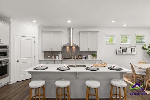 223 Flat Shoals Dr, Bonaire, GA 31005 - kitchen featuring ornamental molding, wall chimney exhaust hood, sink, and a center island with sink