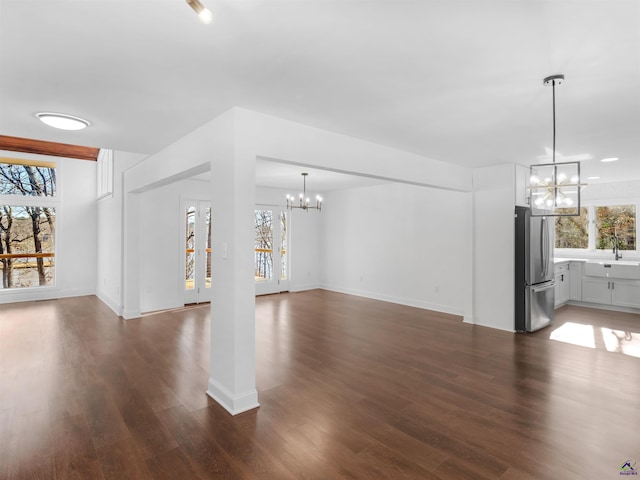 unfurnished living room with dark hardwood / wood-style floors, a chandelier, and sink