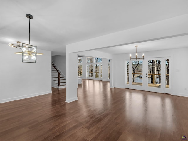 unfurnished living room with dark hardwood / wood-style floors, a notable chandelier, and french doors