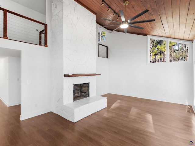 unfurnished living room with lofted ceiling, wood ceiling, hardwood / wood-style flooring, ceiling fan, and a stone fireplace