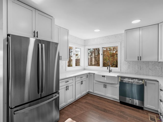 kitchen featuring sink, white cabinets, decorative backsplash, stainless steel appliances, and dark wood-type flooring