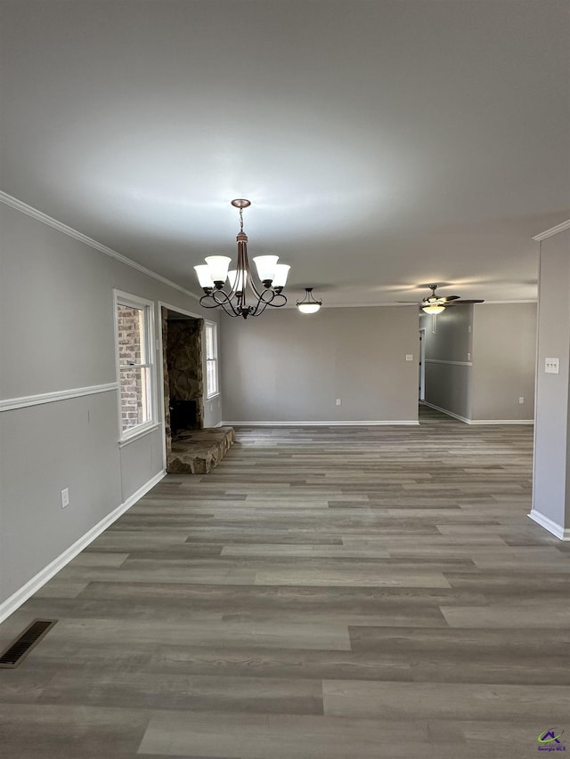 unfurnished dining area featuring crown molding, wood-type flooring, and ceiling fan with notable chandelier