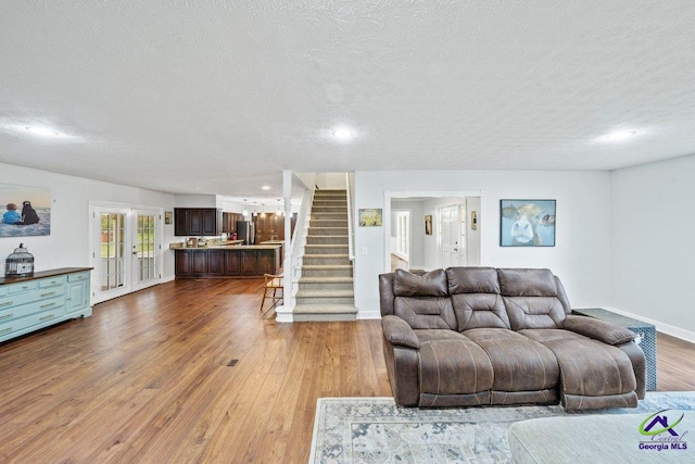 living room featuring french doors, wood-type flooring, and a textured ceiling