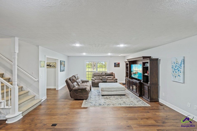 living room featuring dark wood-type flooring and a textured ceiling