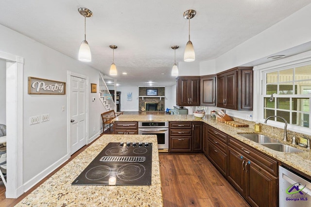 kitchen featuring sink, dark wood-type flooring, appliances with stainless steel finishes, light stone countertops, and decorative light fixtures