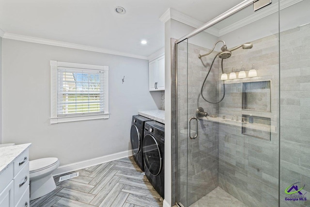 bathroom featuring a shower with door, independent washer and dryer, vanity, ornamental molding, and toilet