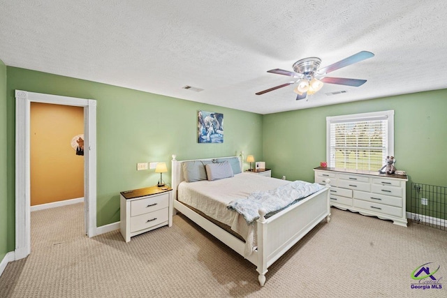 bedroom featuring light colored carpet, a textured ceiling, and ceiling fan