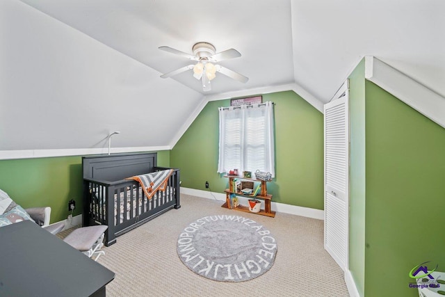 bedroom featuring a nursery area, lofted ceiling, light carpet, and ceiling fan