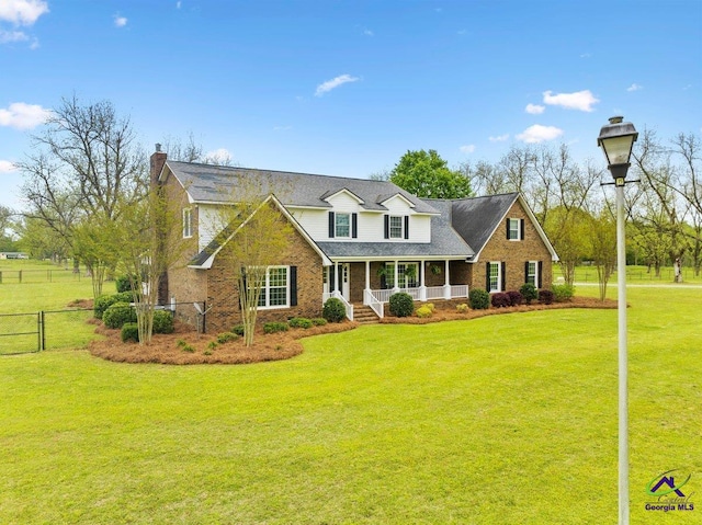 new england style home featuring a front yard and covered porch