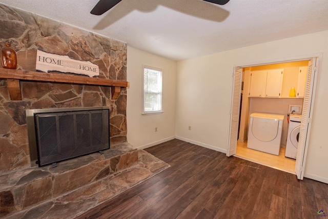 unfurnished living room featuring ceiling fan, a stone fireplace, dark wood-type flooring, and washing machine and clothes dryer