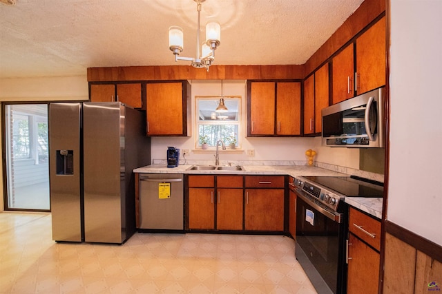 kitchen featuring sink, hanging light fixtures, a notable chandelier, stainless steel appliances, and a textured ceiling