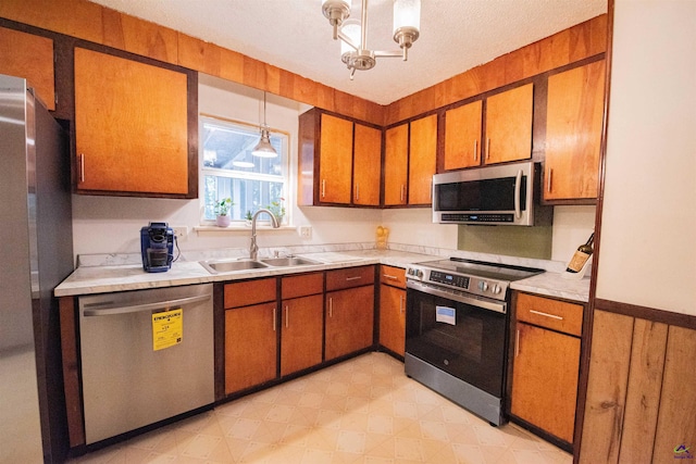 kitchen featuring pendant lighting, sink, a textured ceiling, and appliances with stainless steel finishes