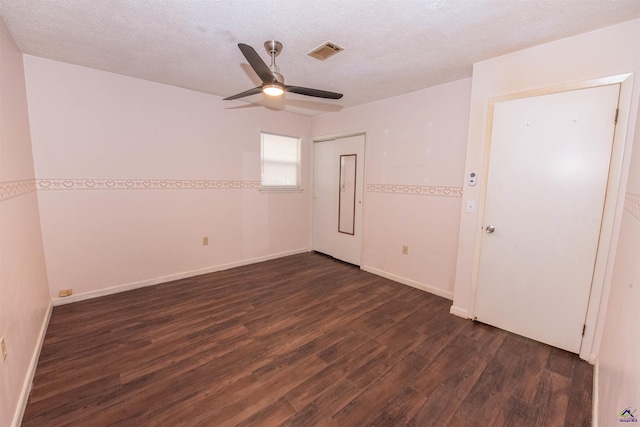 empty room featuring ceiling fan, dark wood-type flooring, and a textured ceiling