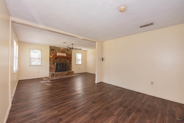 unfurnished living room featuring ceiling fan, a fireplace, dark hardwood / wood-style floors, and a textured ceiling