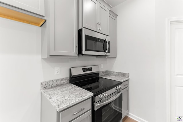687 Jasmine Dr, Macon, GA 31211 - kitchen with stainless steel appliances, gray cabinets, light stone counters, and baseboards