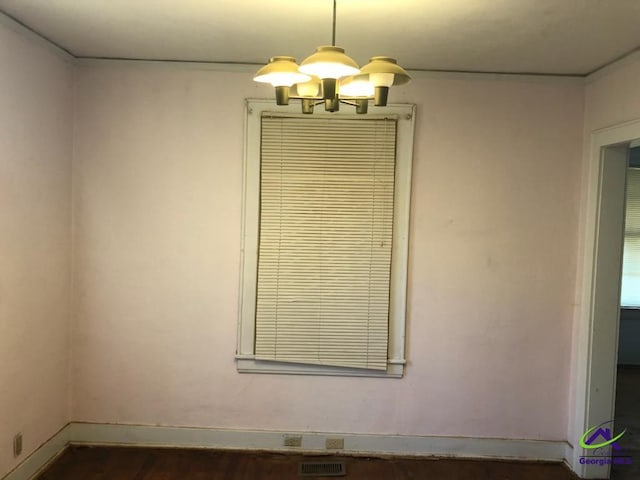 spare room with dark hardwood / wood-style floors and a chandelier