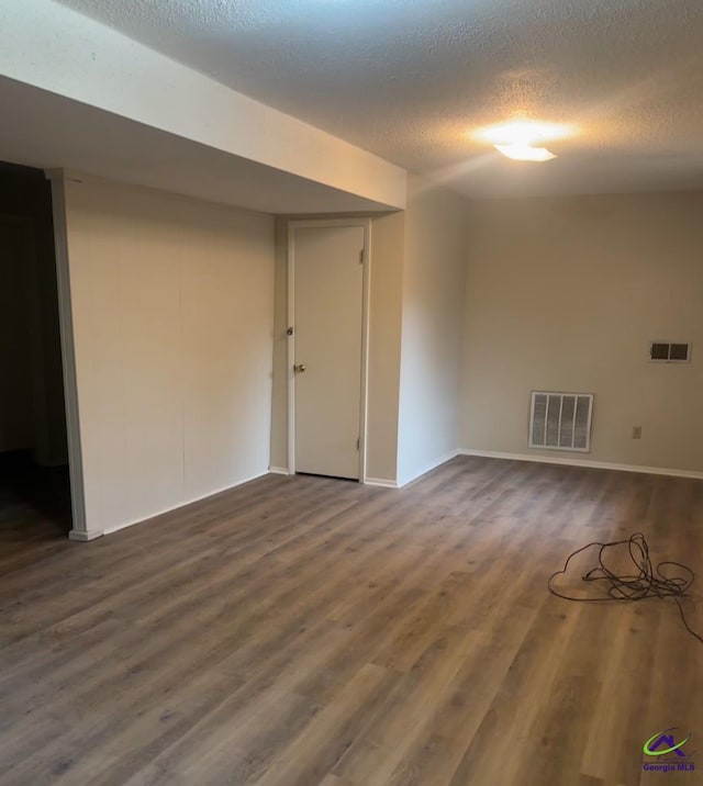 basement featuring dark wood-type flooring and a textured ceiling