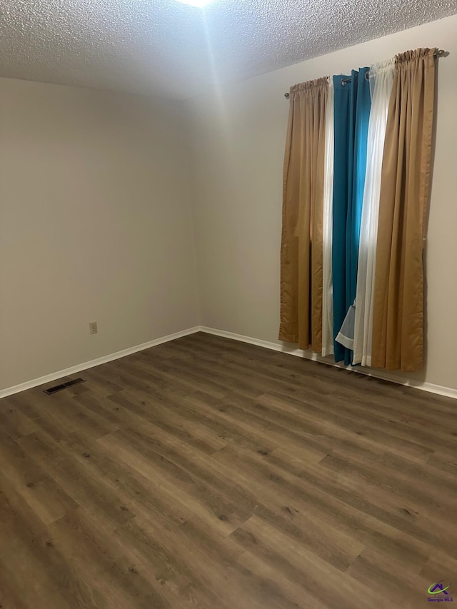 spare room with dark hardwood / wood-style flooring and a textured ceiling